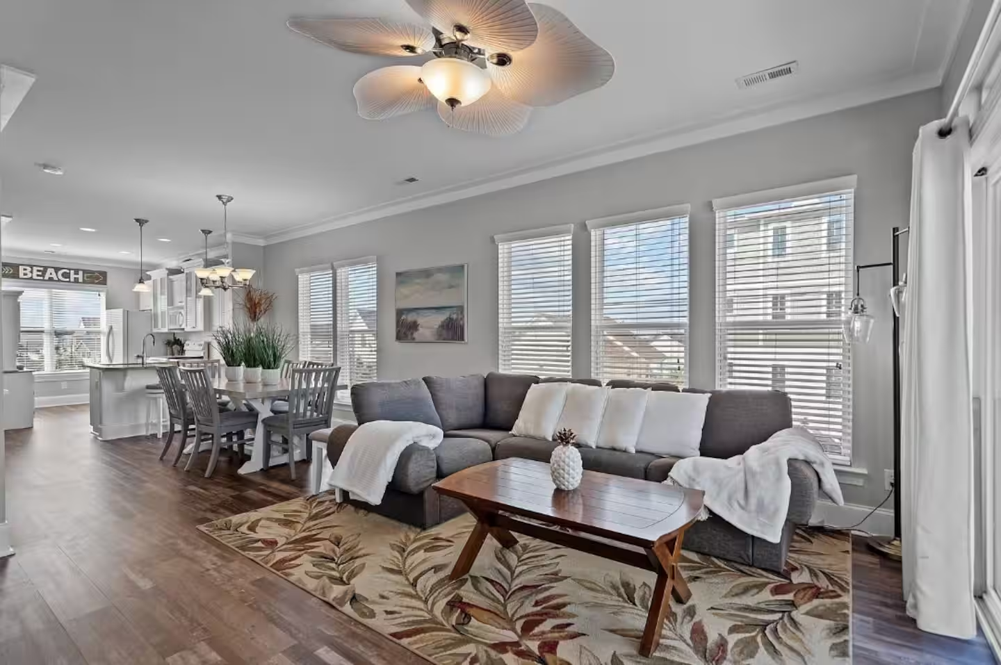 Bright open living room at Shore Thing Y’all with a wraparound couch, dining area, and adjoining kitchen